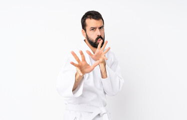 Wall Mural - Young man doing karate over isolated white background nervous stretching hands to the front