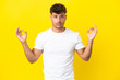 Young caucasian handsome man isolated on yellow background in zen pose