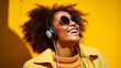 A woman joyfully listening on her smartphone on yellow background