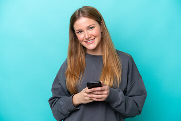Canvas Print - Young caucasian woman isolated on blue background sending a message with the mobile