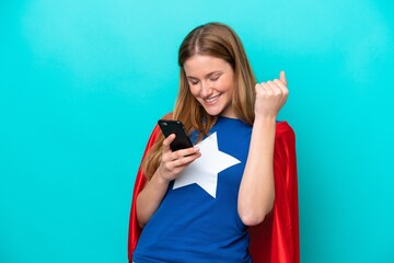 Wall Mural - Super Hero caucasian woman isolated on blue background with phone in victory position