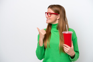 Wall Mural - Young caucasian woman drinking soda isolated on white background pointing to the side to present a product