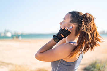 Wall Mural - Young pretty sport woman wearing sport wear and listening music with wireless headphones