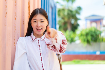 Wall Mural - Young Chinese woman at outdoors surprised and pointing front