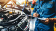 An auto mechanic with a clipboard checking a car in an auto repair shop