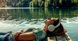 A woman is relaxing on a pier by the lake, listening to music through headphones.