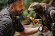 A man is holding a bird with its talons in his hand