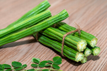 Poster - Moringa Oleifera or drumstick vegetable with leaves on wooden background