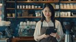 Generative AI : young Asian female coffee shop owner or waitress stands in front of the cashier counter with her tablet. 