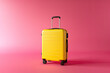 Yellow modern suitcase on pink background