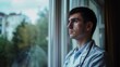 male doctor looks out the window with a thoughtful look