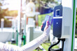 EV Driver use smartphone to scan QR Code on electric vehicle charging stations to pay for electricity. The concept of QR scanning payment instead of cash.
