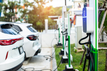 EV charging station with blurry an electric car. Power supply for electric car charging. Socket for electrical car battery charger. EV car charging station in parking. Nature energy, Green eco concept