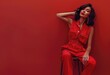 Red Elegance in Monochrome, Fashion portrait of a model in a chic red jumpsuit posing elegantly on a stool, with a matching red backdrop exuding confidence and style