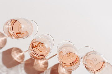 Wall Mural - Many glasses of rose wine Minimal style flat lay. Aesthetic top view wineglass at sunlight, sun shadows and shiny glass. Light alcohol drinks for summer party, fun events. Flat lay, copy space