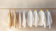 Minimal fashion clothes concept. Male shirts hanging on wooden hangers against a plain background. White, and beige colors. Wardrobe, clothing storage, showroom, fashion store.