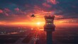 Air traffic control tower overseeing an airplanes sunset landing, radiating sky in the backdrop