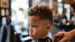 Side view of little boy getting a haircut at a barbershop