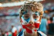 A young boy with a British flag painted on his face stands in a stadium. Football fans at the football championship