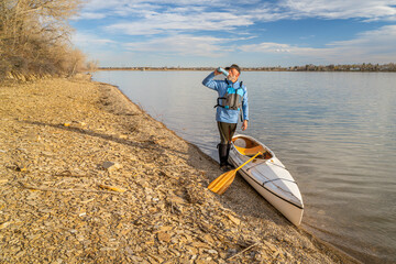 Wall Mural - senior male paddler with expedition decked canoe on a lake shore in early spring, Boedecker Reservoir in northern Colorado