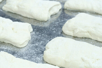 Poster - Conveyor belt with pieces of cheese dough ready to be placed in a mold and baked in different shapes and sizes, all lined up on the conveyor belt.