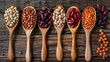 Assortment of beans and lentils in wooden spoon on wooden background.