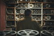 In an old film lab, a cameraman sifts through dusty reels. His eyes reveal a mix of regret and sorrow--the lost moments he failed to capture, now forever elusive.
