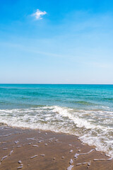 Wall Mural - waves gently crashing on beach with blue sky