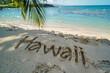 © ink drop - Hawaii written in the sand on a beach. Hawaiian tourism and vacation background