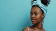 African woman adorned with a light blue turban, showcasing her natural beauty with a confident gaze, embodying self-care idea