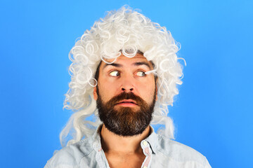 Sticker - Portrait of surprised man with beard and mustache in white wig. Party time. Stylish bearded male model in curly wig. Fashion concept. Handsome hipster in periwig looking away. Barbershop advertising.