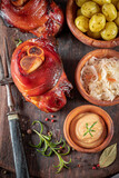 Fototapeta  - Aromatic roasted pork knuckle served with sauerkraut and potatoes.