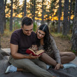 © Miljan Živković - Man and woman young adult couple in nature hold and read book in love