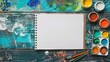 Table with paintings brush and sketchbook empty sheet top view wallpaper background