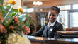 A friendly hotel receptionist warmly welcoming guests with a smile at the front desk.