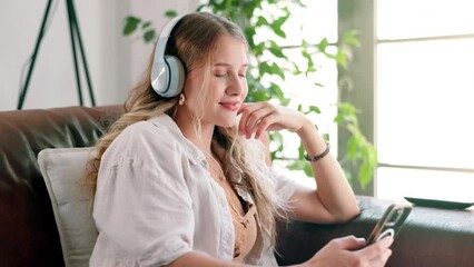 Poster - Cellphone, headphones and woman on sofa at house networking on social media, mobile app or internet. Smile, typing and female person listening to music, radio or album on phone in living room at home