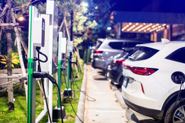 Wall Mural - EV charging station with blurry an electric car. Power supply for electric car charging. Socket for electrical car battery charger. EV car charging station in parking. Nature energy, Green eco concept