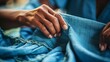 a woman's hand sewing a piece of blue fabric 