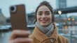 © Nataliya - Young happy caucasian fashionable woman taking selfie outdoors during winter in the city. Social media report