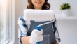© Marko - young Woman painting a room wall with paint roller