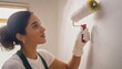 © Marko - young Woman painting a room wall with paint roller