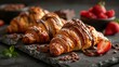   Croissants topped with melted chocolate and fresh strawberries arranged elegantly on a wooden slate