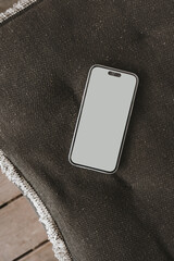 Wall Mural - Mobile phone with blank screen on black pillow. Flat lay, top view template with copy space