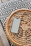 Fototapeta Tulipany - Mobile phone with blank screen on ornamental wooden table and carpet. Flat lay, top view template with copy space