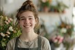 © ChaoticMind - A happy young florist in an apron stands amidst blooming flowers and plants