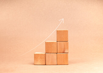 Poster - Rising up thin arrow on wooden cube blocks, minimalist bar graph chart steps on brown recycle paper background, profit, benefit, income, business growth process, trend, economic improvement concepts.