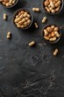 A set of peanuts in bowls on a black stone background. Walnut background. View from above. place for text. generative ai