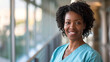 Young black female doctor in blue scrubs, smiling looking in camera, Portrait of woman medic professional, hospital physician, confident practitioner or surgeon at work. blurred background