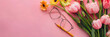 Blooming flowers, rimless glasses and mechanical pencil on a pink chalkboard background with copy space for Teacher’s Day or Women’s Day concept