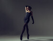 ballerina in total black style in a dress and tights poses silhouetted elements of ballet